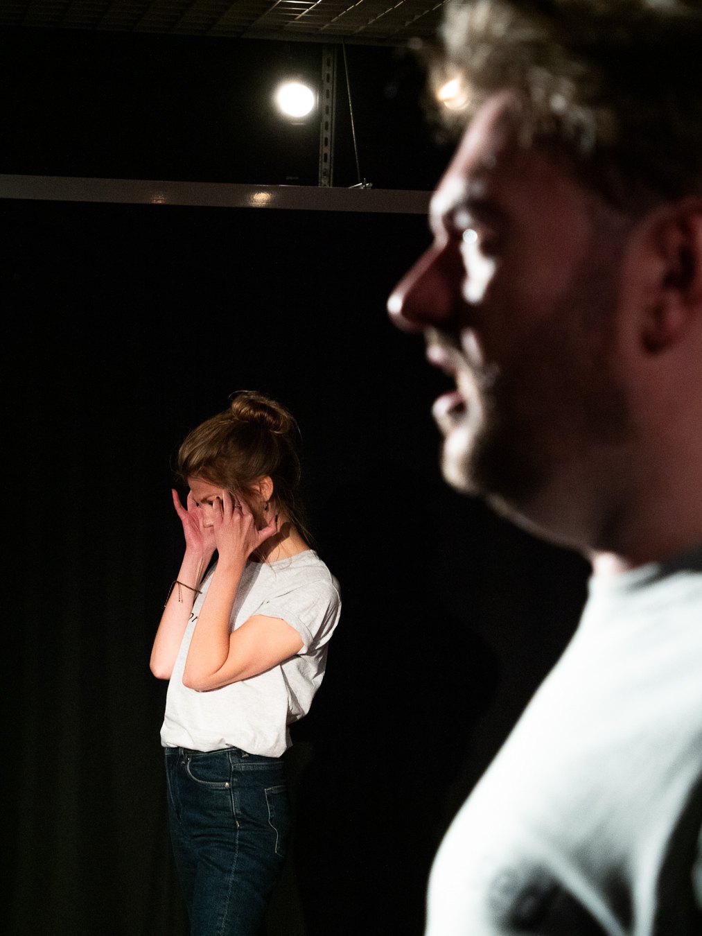 Emily Matthews covering her face while Tom Gilder performs in the foreground